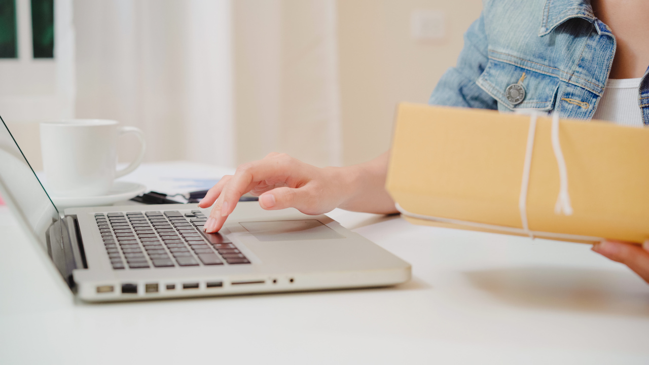 mulher digitando no computador com embalagem de armazenamento na mão para realizar o controle de estoque